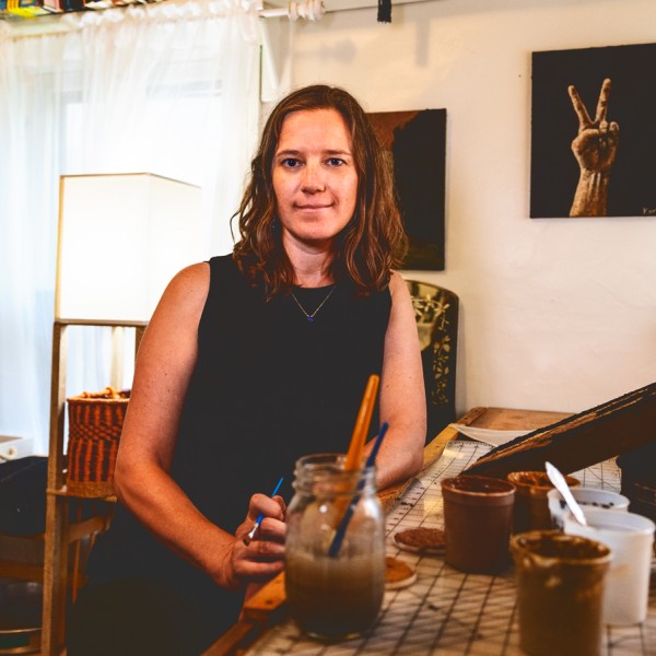 kirsten kurtz at artist bench with soil paintings in the background