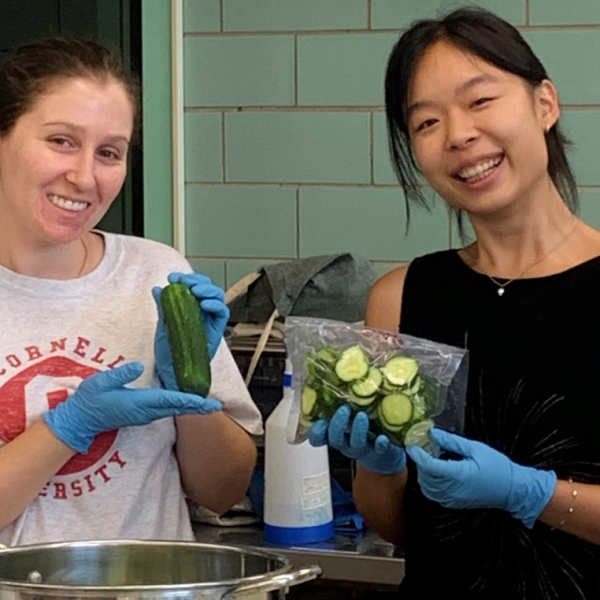 Graduate students Danielle Heaney and April Huang pose with cucumbers they are preparing for research at the High Pressure Processing Validation Center.