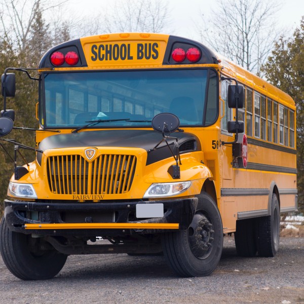 A yellow school bus with trees in the background. 