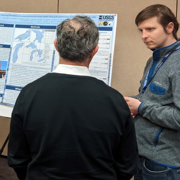 Person discussing presentation poster on saildrones with another person