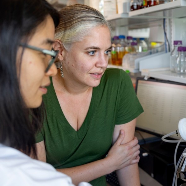 Two women look at a screen on lab equiptment.