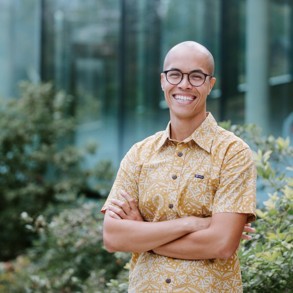 Steven Mana'oakamai Johnson wearing a yellow and white shirt standing with arms folded.