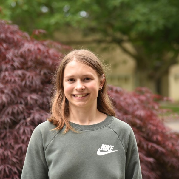 Gretchen Wittmeyer '24 posing, smiling in front of a Japanese Maple