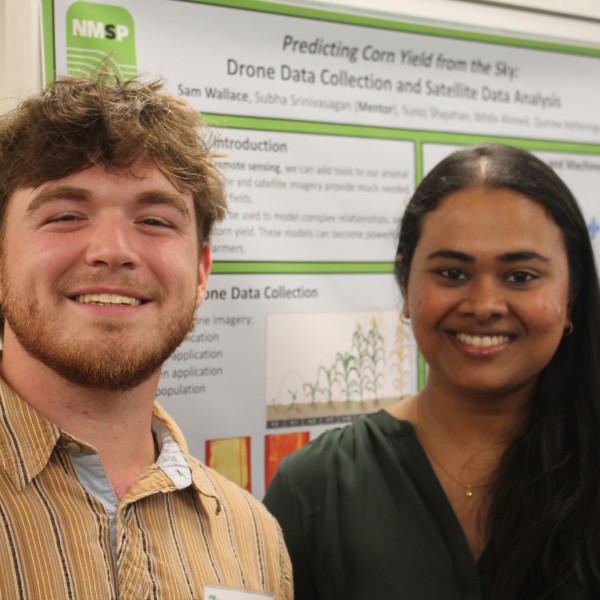 Two people in front of a poster