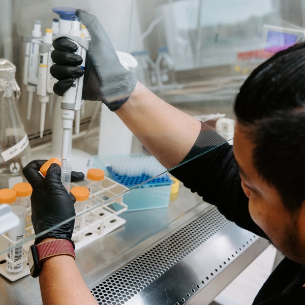A man using a mechanical pipette inside a lab. 