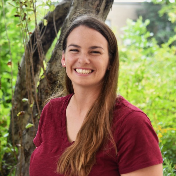 Headshot of Carly Bass smiling in front of a tree