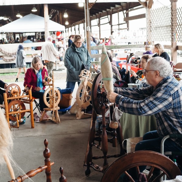 A group of people spin fiber on spinning wheels 