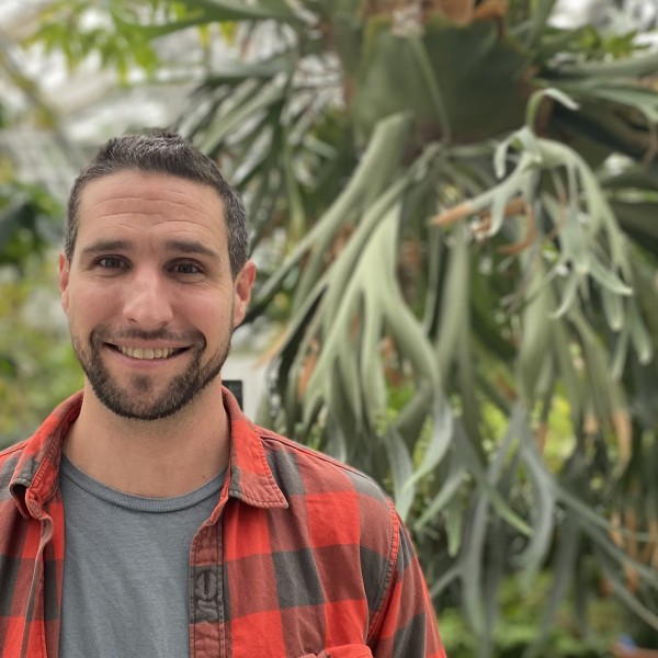 Joshua Manser in front of plants in a greenhouse
