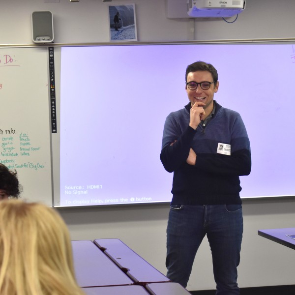 a man stands in front of students, teaching