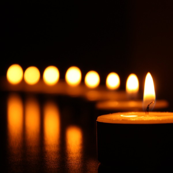 A row of lit candles in a black room.