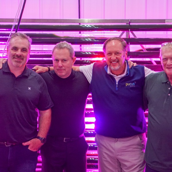 Four men standing in front of a purple UV light. 