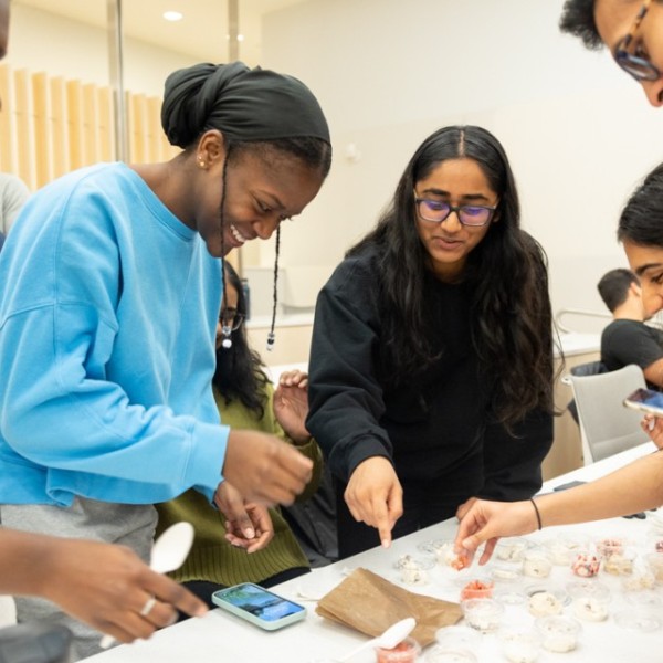 Four students gather around a table trying different ice cream flavors in small bowls.