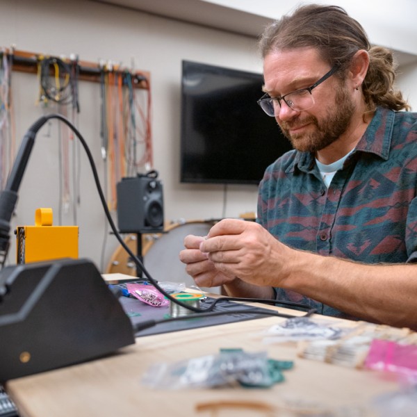 A man solders microchips in a technology lab.