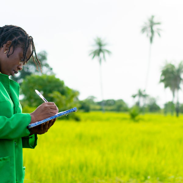 woman in green takes notes in a field