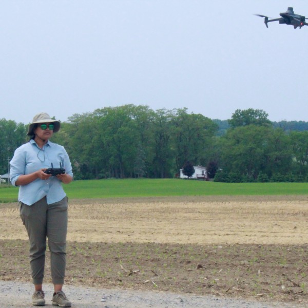 a woman in field with drone camera