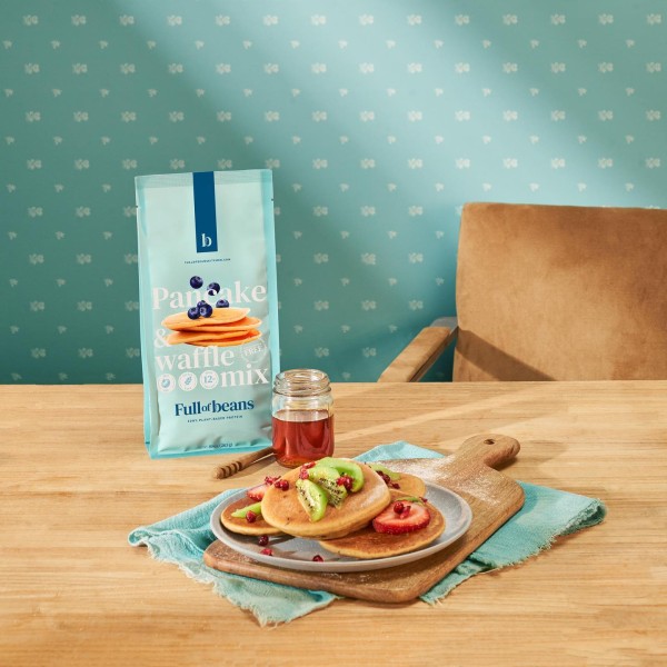 A blue bag of pancake mix next to a plate of pancakes. 
