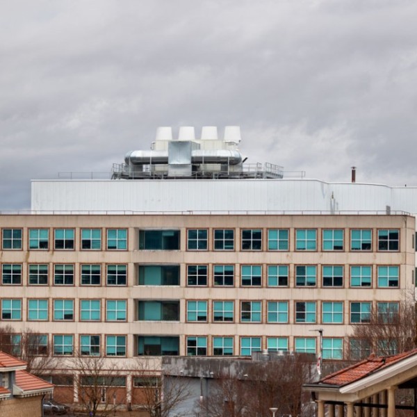 The outside of the Biotechnology Building on a grey cloudy day. It is a building with five floors, peach concrete walls, and sixteen windows per floor covering the entire span of the building.  