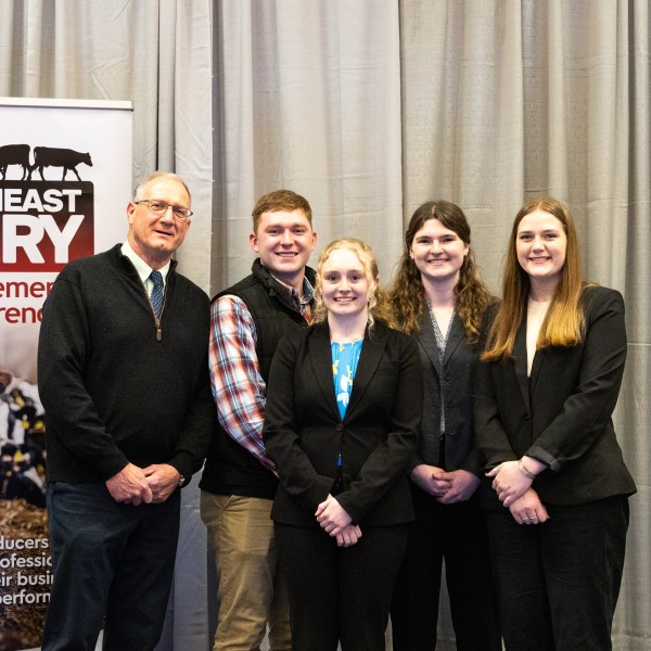 Five people standing in front of a conference banner
