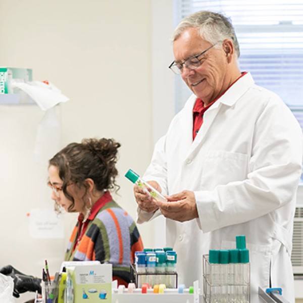 bridgen in while coat looking at glass tube