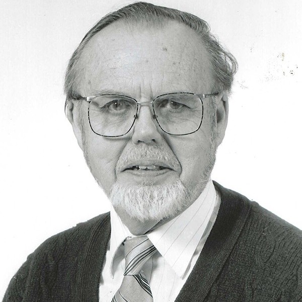 Headshot of Richard Robinson. An older man in a suit wearing glasses.