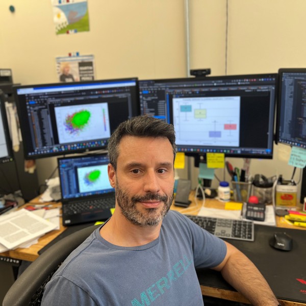 a man sits in front of many computer monitors