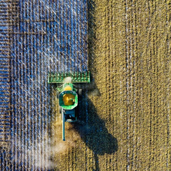 An aerial view of a tractor cutting down field crops.