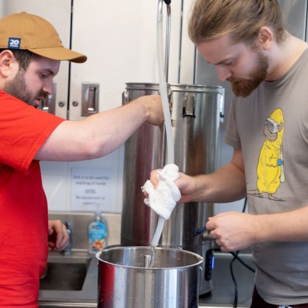 Dean Hauser, left, and Andy Kalenak “sparge” the grain bed, running very hot water through to fully extract the sugars from the grains