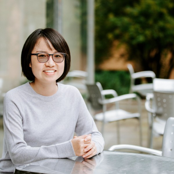 a woman sits at a table outside