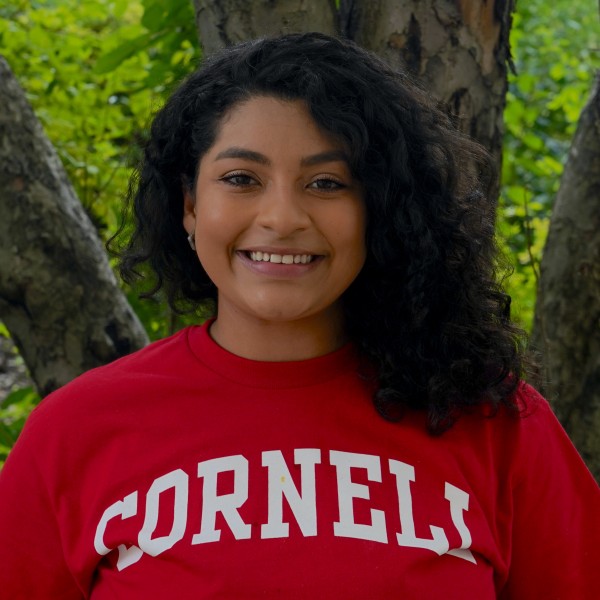 Woman smiling in front of a tree.