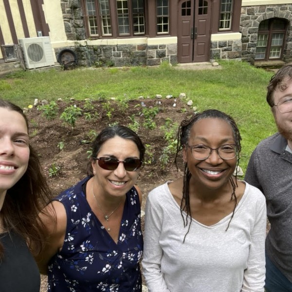 individuals smile in front of pollinator gardens