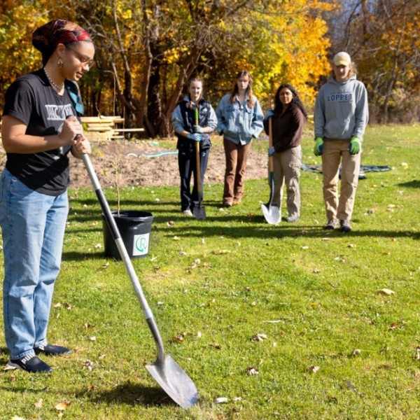 Gracekelly Fulton '24, co-lead of the Sustainable Landscapes team, prepares to plant a wild plum tree outside Onondaga Nation School. Photo by Sreang Hok.
