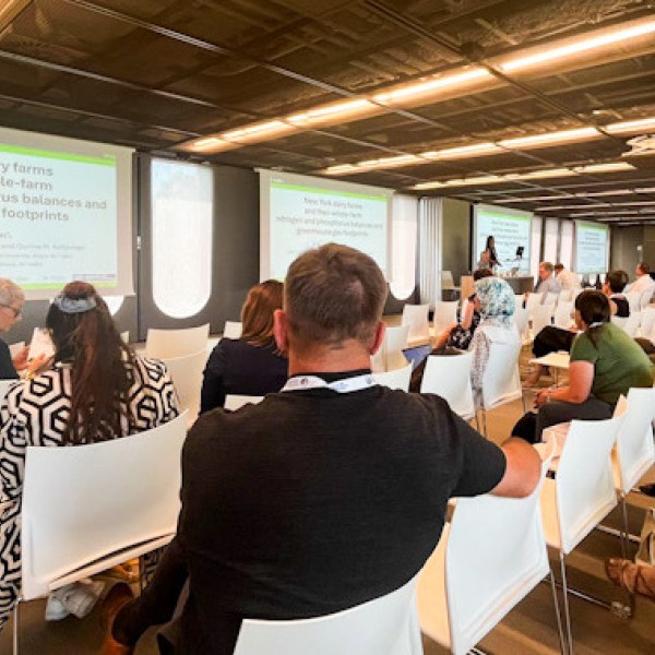 People sitting in white chairs and a slideshow presentation at the front of the room.