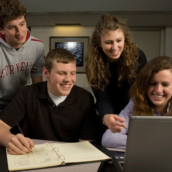 two men and two women study a computer screen together