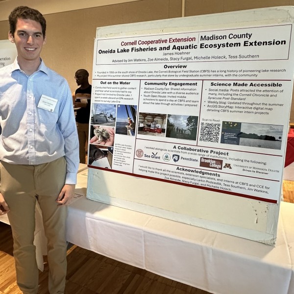 Student standing next to research poster