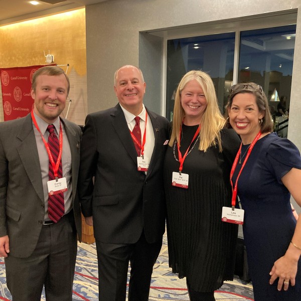 4 individuals stand and smile for a picture