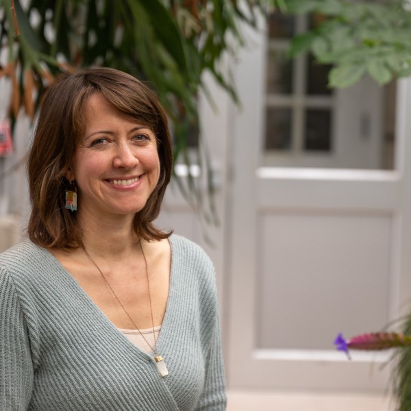 A woman stands in a greenhouse
