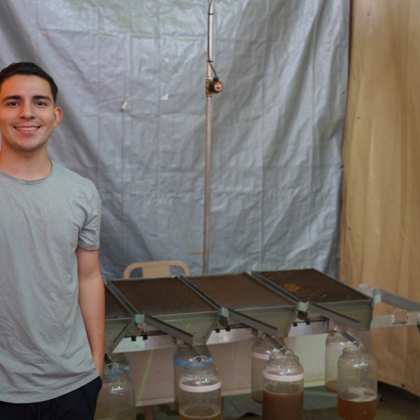 A man stands next to research equipment, smiling.
