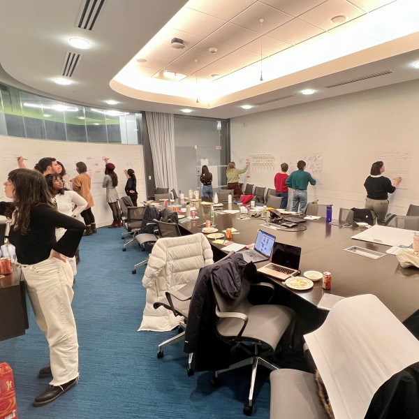 Students and professors write on collaborative wall