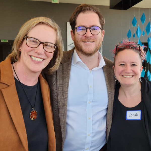 Group of three poses in front of blue hanging decoration