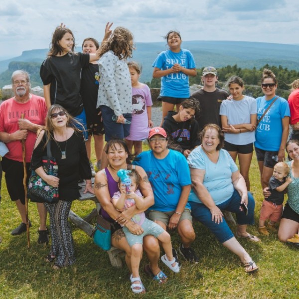 Group photo of people of all ages posing in front of a mountainside 