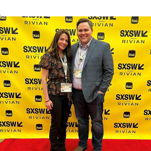 two pose on red carpet in front of yellow background 