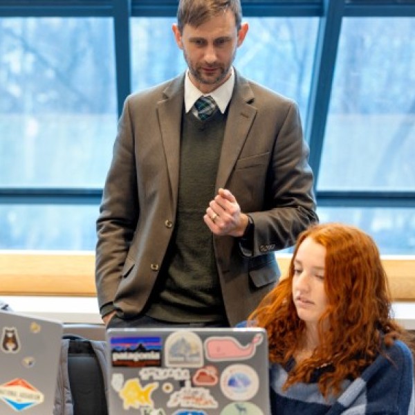 Ault stands behind two students who are showing him something on their laptops.