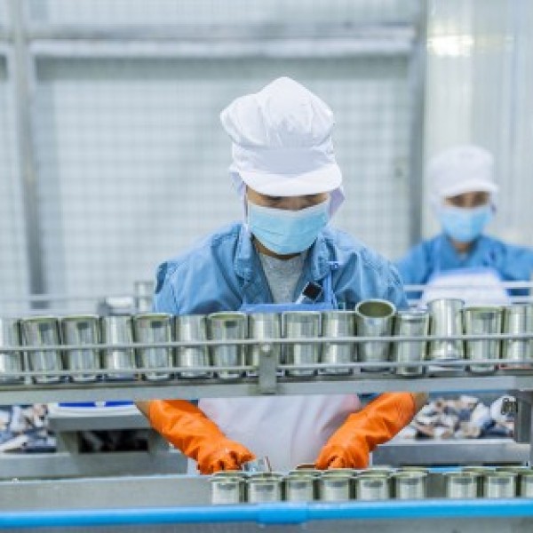 A person works on a production line wearing protective gear