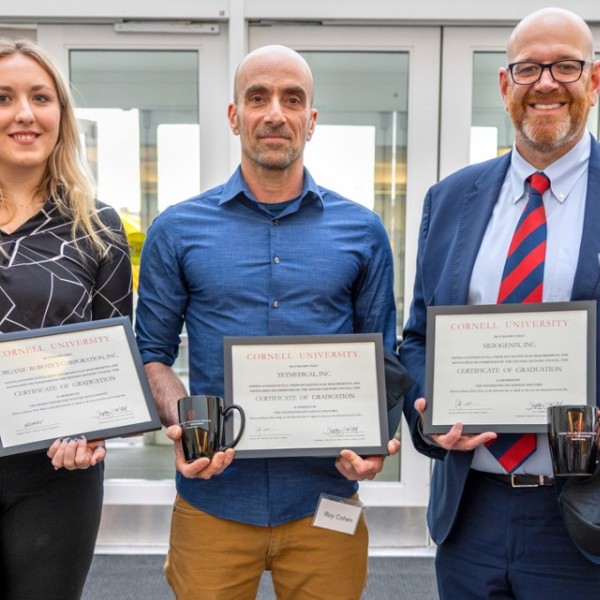 Melanie Lyons, M.Eng ’22, biomedical engineer at Llume; Roy Cohen, co-founder of TETmedical; and Ricardo Garcia de Alba, CEO of Meiogenix, show the certificates and mugs they received at the April 15 incubator graduation ceremony at Weill Hall.