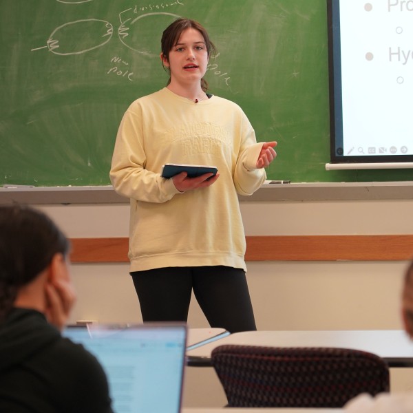 a woman stands in front of a class, talking