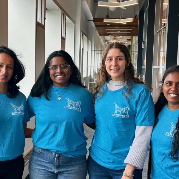 Students in bright blue shirts pose in comm department hallway