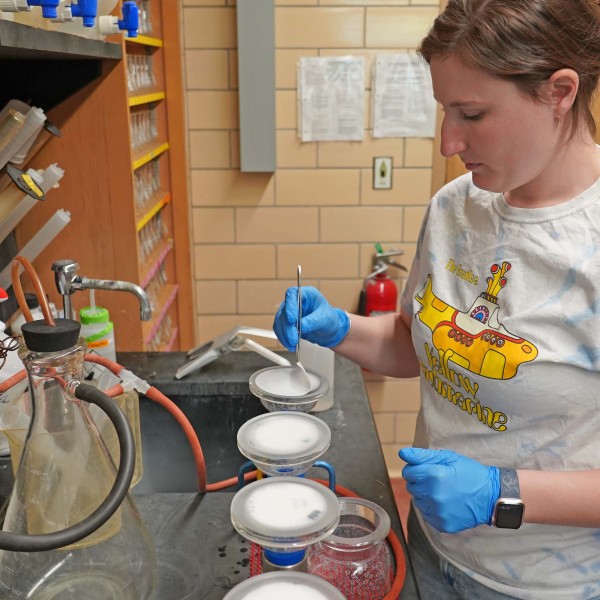 a woman picks up a filter with tweezers in a lab
