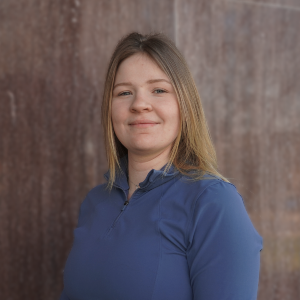 A woman smiles in front of a wall.