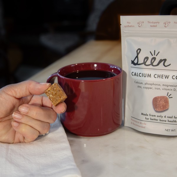 A Seen Nutrition calcium chew posed next to a cup of coffee. 