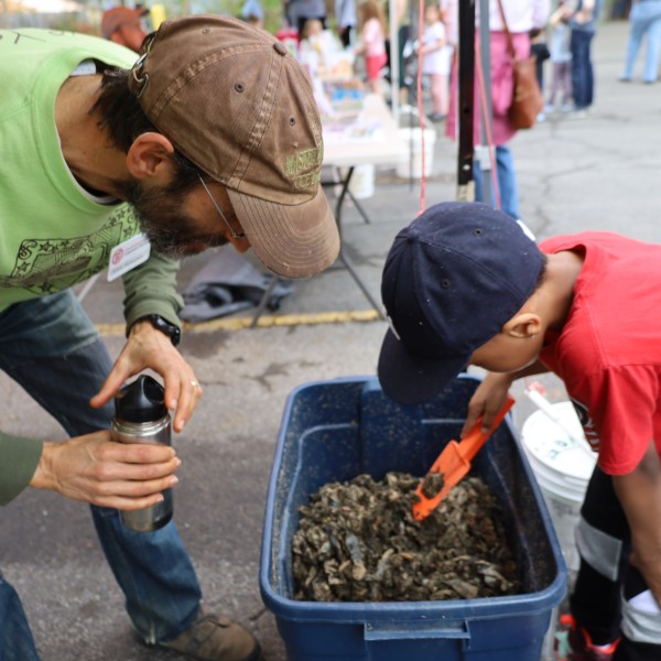 Two people look at a vermicompost box